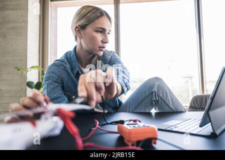 Woman examining drone through tablet PC in office Stock Photo