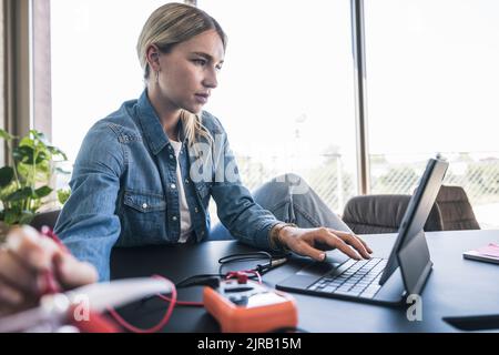 Woman programming drone using tablet PC at desk in office Stock Photo