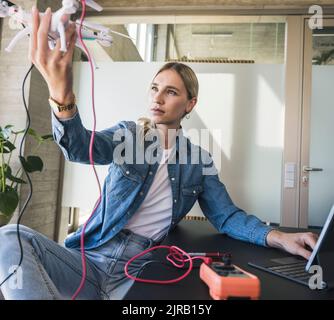Woman analyzing drone sitting at desk in office Stock Photo