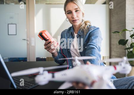 Woman measuring voltage of drone through multimeter in office Stock Photo