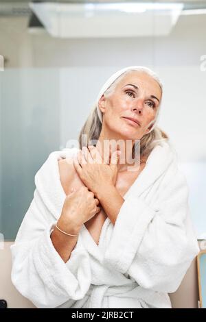 Woman massaging neck in front of mirror Stock Photo - Alamy