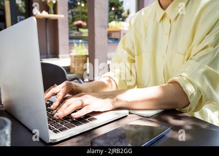 Hands of freelancer using laptop at sidewalk cafe Stock Photo