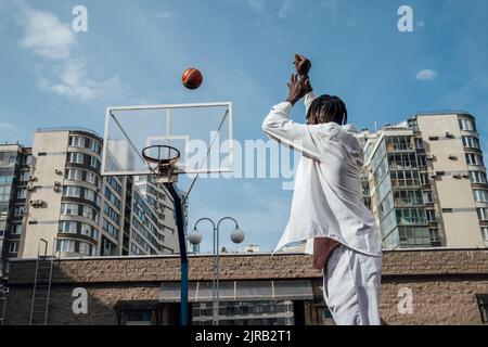 Young man throwing basketball in hoop Stock Photo