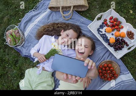 Cheerful girl taking selfie with sister through smart phone in park Stock Photo
