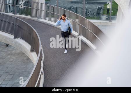 Young businessman with bag talking on mobile phone Stock Photo