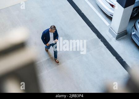 Businessman using mobile phone walking in parking lot Stock Photo