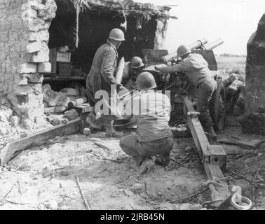 A vintage photo circa February 1943 of American soldiers manning a 105 mm howitzer, Battery B 33rd Field Artillery during fighting at the Kasserine Pass in Tunisia, North Africa Stock Photo