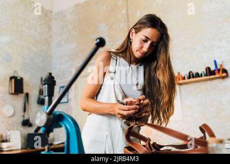 Fashion designer making leather accessory at workshop Stock Photo