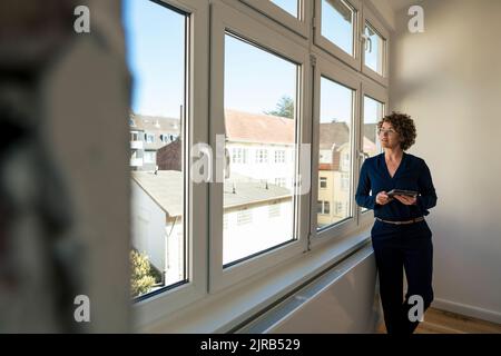 Real estate agent with tablet PC looking through window Stock Photo