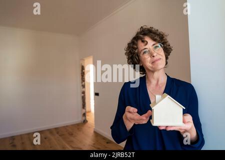 Smiling real estate agent showing model house Stock Photo