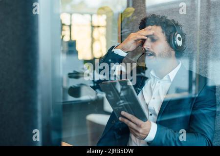 Businessman using tablet computer seen through glass of workplace Stock Photo