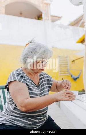 Senior woman preparing hair dye in bowl on table Stock Photo