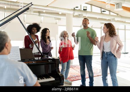 Businessman singing by colleagues snapping fingers Stock Photo