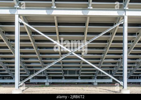 Straight on view of under stadium bleachers, steal I-Beam bleachers with X cross brace, with stone surface. Stock Photo