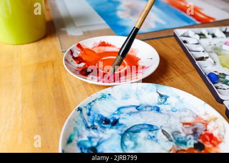 Paintbrush in red watercolor on table Stock Photo