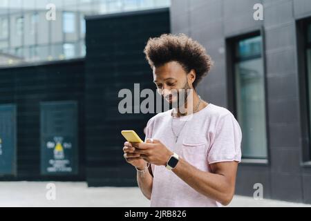 Smiling man using mobile phone near building Stock Photo