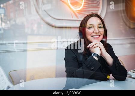 Happy young woman seen through glass at cafe Stock Photo