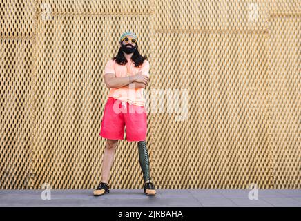 Hipster man with prosthetic leg standing in front of wall Stock Photo