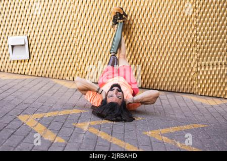 Smiling bearded man with prosthetic leg lying on road Stock Photo