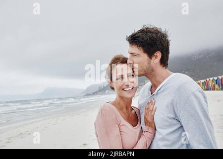 Affecionate man kissing woman on forehead standing at the sea Stock Photo