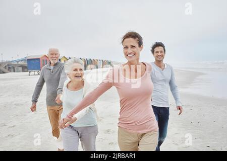 Adult couple walking with senior parents on the beach Stock Photo