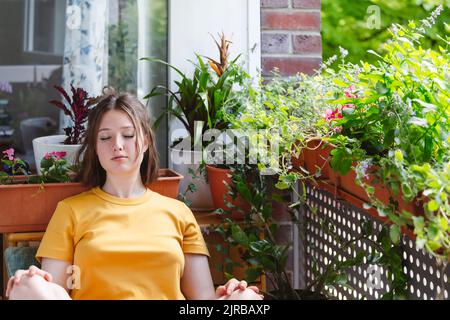 Teenage girl with eyes closed relaxing on balcony Stock Photo
