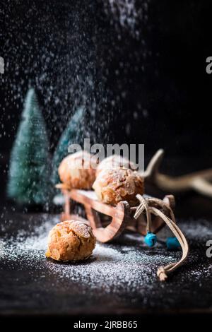 Studio shot of powdered sugar pouring on miniature sled with almond cookies Stock Photo