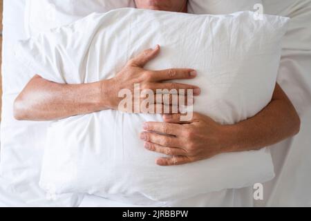 Mature man with pillow sleeping in bed Stock Photo