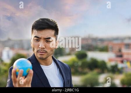 Young businessman staring at globe Stock Photo