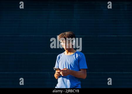 Smiling man wearing headphones using smart phone Stock Photo