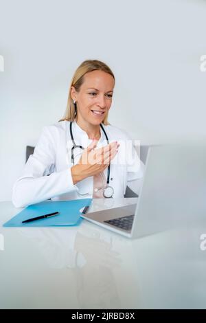 Smiling female doctor using laptop at desk in medical practice Stock Photo