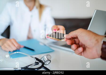 Patient handing over card to doctor in medical practice Stock Photo