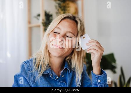 Smiling woman with eyes closed holding credit card Stock Photo
