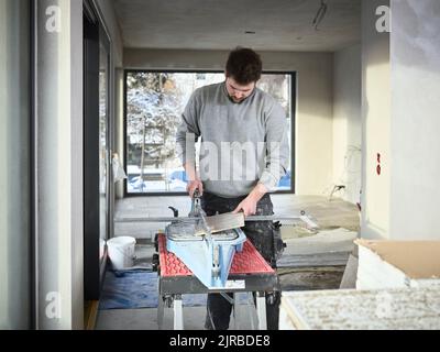 Tiler cutting tiles with equipment at construction site Stock Photo