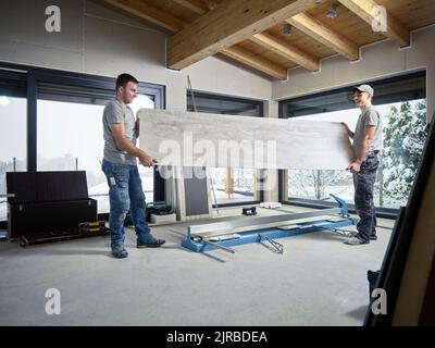 Happy tilers holding large tile at construction site Stock Photo