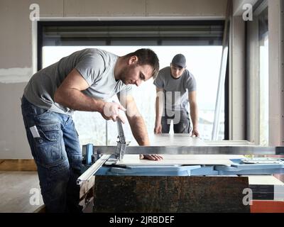 Tiler cutting tile with machine at construction site Stock Photo