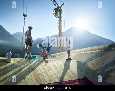 Carpenters working together on roof at construction site Stock Photo