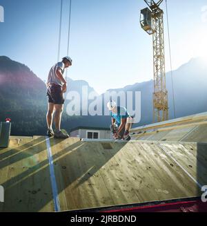 Carpenter with drill working on roof at construction site Stock Photo