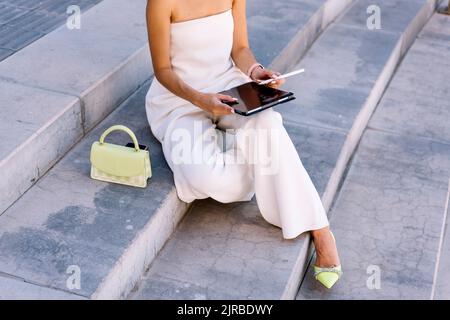 Woman using tablet PC sitting on steps Stock Photo
