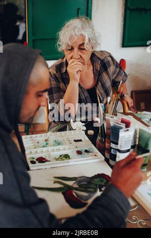 Senior woman looking at artist painting on paper Stock Photo