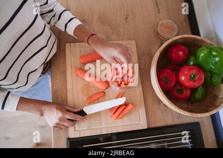 Woman putting slices of carrots in jar at home Stock Photo