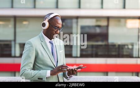 Mature businessman wearing wireless headphones using tablet PC Stock Photo