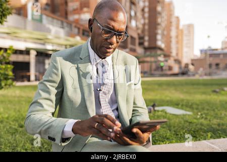Businessman wearing In-ear headphones using tablet PC at financial district Stock Photo