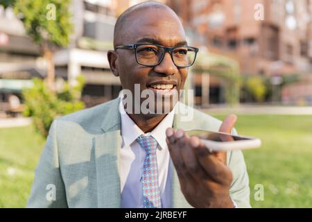 Smiling businessman talking on smart phone speaker Stock Photo