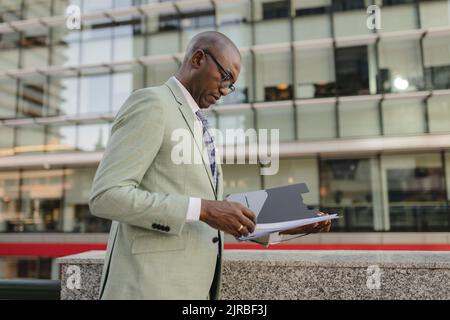Businessman examining documents standing at financial district Stock Photo