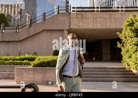 Mature businessman with backpack walking in financial district Stock Photo
