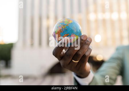 Hand of mature businessman holding globe figurine Stock Photo