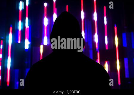 Man wearing hooded shirt in front of illuminated lights Stock Photo