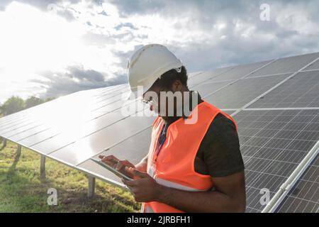Man with hardhat using tablet PC at solar station Stock Photo