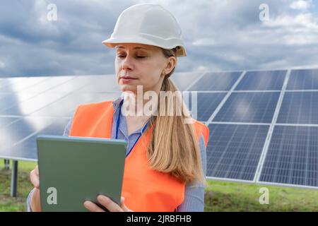 Engineer working on tablet PC in front of solar panels Stock Photo